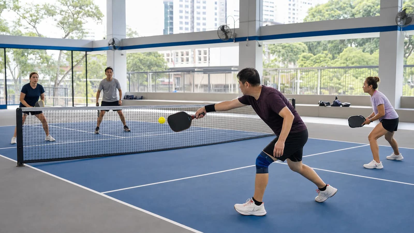 Adults playing doubles pickleball at a covered Singapore community court